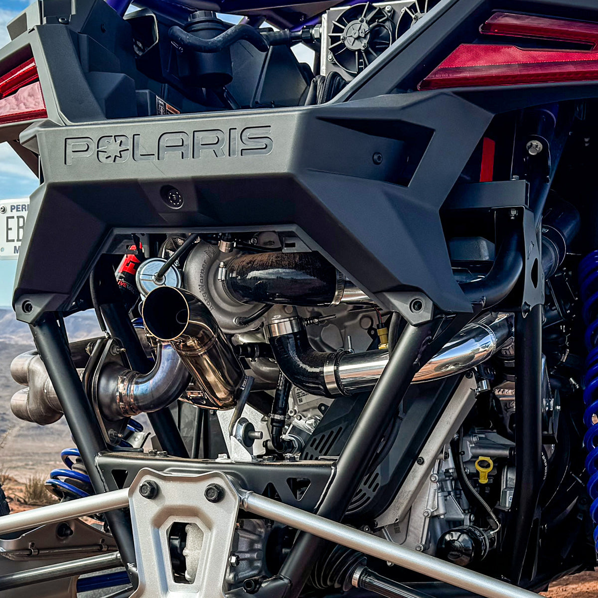 
                  
                    Close-up rear view of a Polaris RZR Pro R featuring the installed H&S Motorsports Easy Boost Turbo Kit, showing polished turbo components and exhaust plumbing.
                  
                