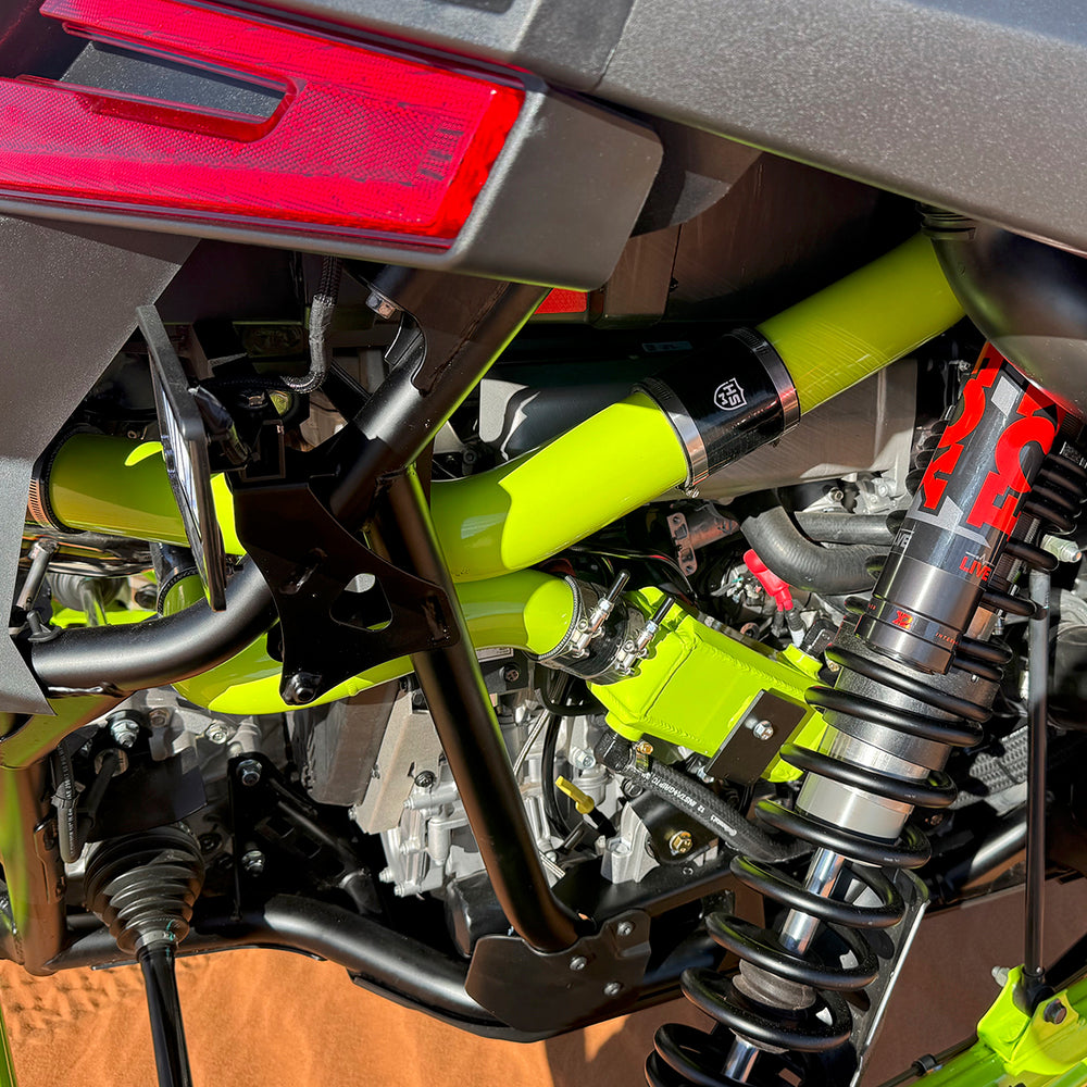
                  
                    Close-up of the rear suspension and intake piping on a Polaris RZR Pro R, highlighting the lime green H&S Motorsports turbo tubing and black couplers with HSM logo.
                  
                