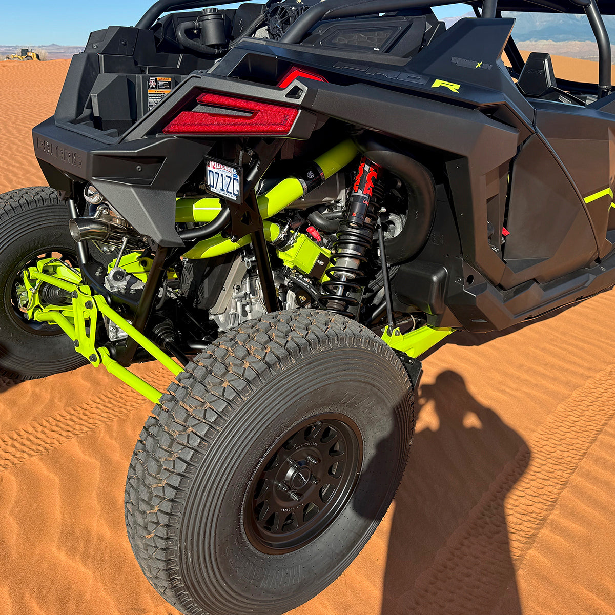 
                  
                    Rear-side view of a Polaris RZR Pro R parked on red sand, showcasing the installed H&S Motorsports Easy-Boost Turbo Kit exhaust tip, suspension components, and aggressive off-road tires.
                  
                