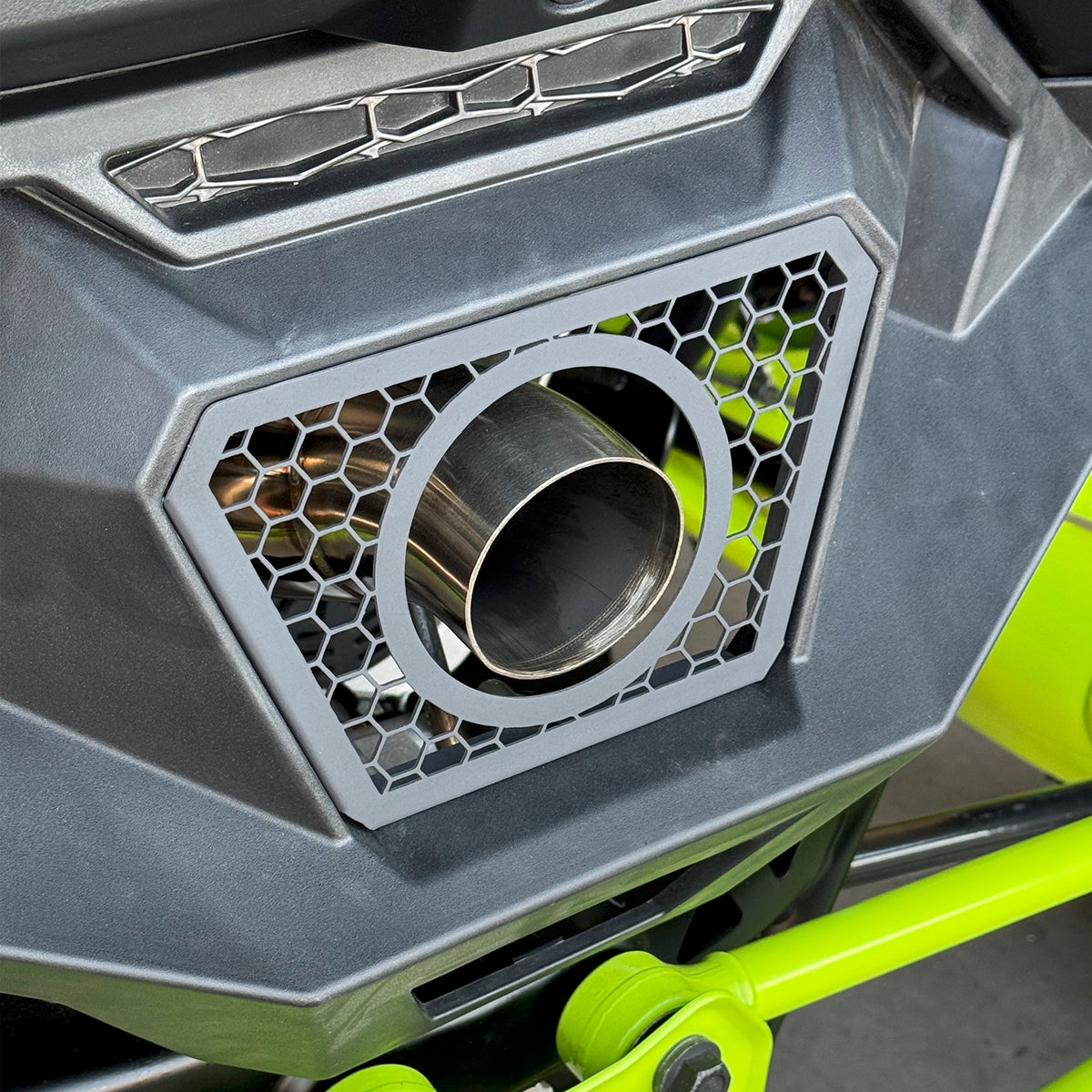 
                  
                    Close-up of the rear exhaust outlet on a Polaris RZR Pro R featuring the H&S Motorsports Easy Boost Turbo Kit, showing a polished tip behind a custom hexagonal grille.
                  
                